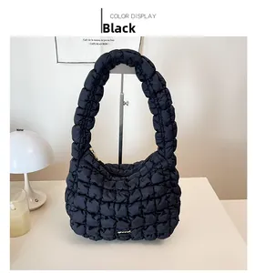 Close-up of black quilted puffer shoulder bag with metallic detail on soft background