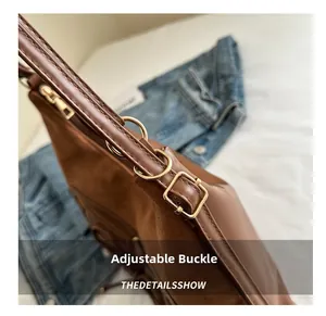 Detail view of brown shoulder bag showing adjustable gold buckle and neat stitching