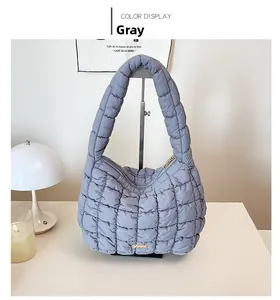 Detail of grey quilted cotton shoulder bag with metallic zipper and soft padded handle