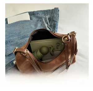 Detail view of large brown suede shoulder bag showing spacious interior with daily items