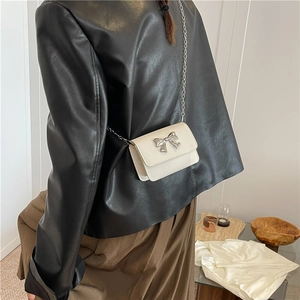 Détail du mini sac blanc à bandoulière avec nœud argenté et fine chaîne métallique