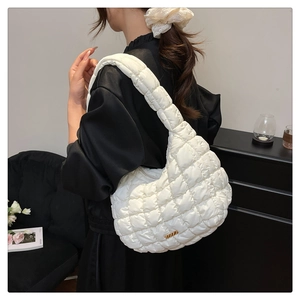 Close-up of quilted nylon fabric texture and gold metal buckle on white shoulder bag