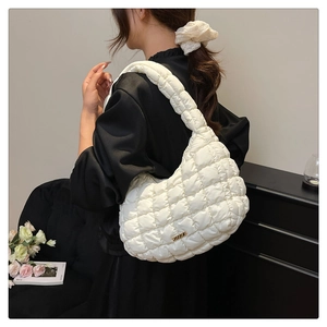 Detail of white quilted puffer shoulder bag with metallic gold logo and soft texture