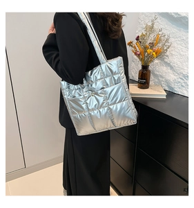 Close-up of silver quilted tote bag with metallic padded texture and square stitching