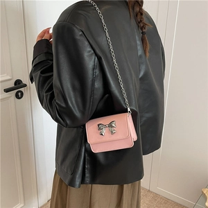 Vue détaillée du mini sac bandoulière rose avec nœud argenté et bandoulière en chaîne