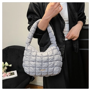 Detail of light gray quilted puffer shoulder bag with a stylish gold metal accent piece