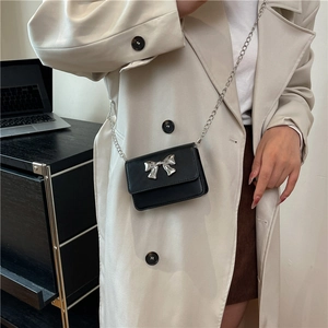 Détail d'un mini sac bandoulière en cuir PU noir avec boucle nœud en métal argenté