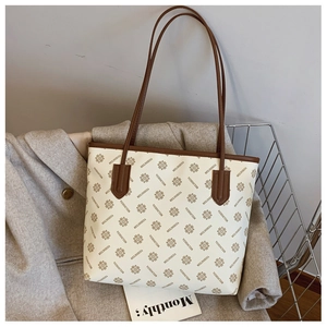 Detail of printed tote bag with brand pattern leaning against a coat and magazine