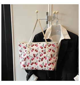 Detail of a white tote bag with red cherry prints hanging on a hanger for daily outfit