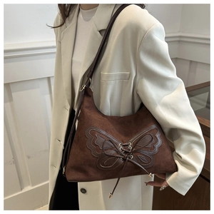 Detail of dark brown suede shoulder bag with butterfly patch and lace-up design