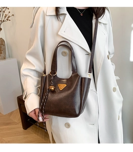 Close-up of vintage dark brown tote bag with gold triangle logo and metal charm