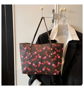 Detail view of brown tote bag with pink cherry print and sturdy faux leather handles