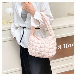 Close-up of pink quilted puffer tote bag with soft padded nylon texture and metal logo