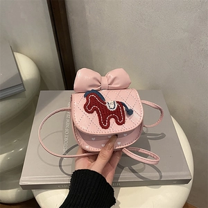 Cute pink quilted girls crossbody bag with bow and pony embroidery on a book