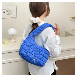 Detail shot of royal blue quilted handbag with plush texture and gold metal tag