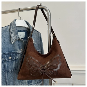 Detail of coffee brown suede tote bag featuring a leather butterfly applique and lace-up design
