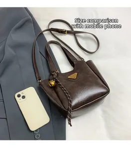 Detail view of dark coffee tote bag showing size comparison with a smartphone