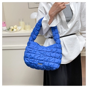 Close-up of royal blue quilted puffy hobo bag with gold logo and pleated texture