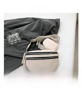 Detail view of cream crossbody bag with textured leather and geometric wide strap