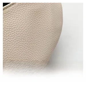 Detailed macro view of cream-colored litchi grain leather texture and fine stitching