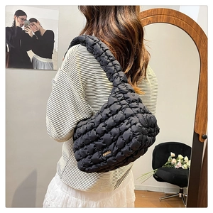 Detail of black quilted puffer bag showing ruched texture and golden metallic logo