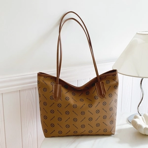 Vintage brown monogram tote bag with floral print and leather straps on marble surface