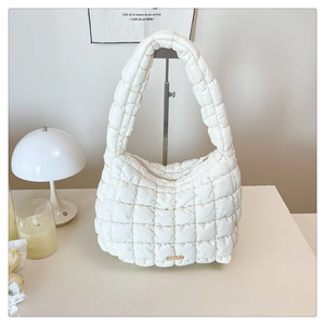 Detail of white quilted bubble shoulder bag with soft textured fabric and gold metal trim
