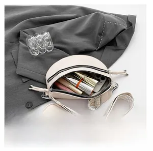 Detailed view of cream crescent crossbody bag with wide strap and small coin pouch