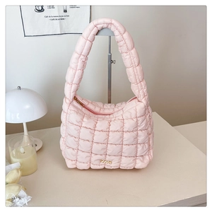 Detailed close-up of pink quilted shoulder bag with zipper and gold plaque