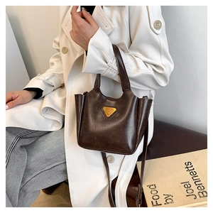 Detailed view of dark brown vintage faux leather tote with golden triangular metal plaque