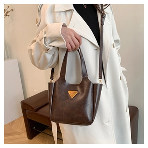 Detail of vintage brown leather tote bag with gold triangle logo and crossbody strap