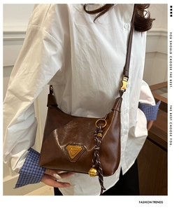 Brown vintage shoulder bag detail with triangle gold logo and tassel bell charm