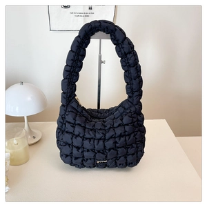 Detail of black quilted puffer bag showing textured fabric and gold logo on the base