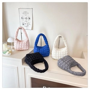 Quilted puffer handbags in five colors displayed on a modern white stepped stand