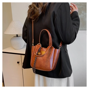 Detail of a brown vintage leather tote with gold hardware shown on a female model