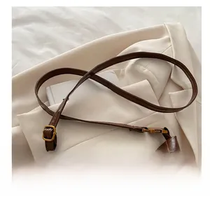 Detail of vintage dark brown shoulder bag strap with gold metal buckle on white suit