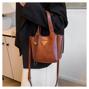 Detail of vintage brown oil wax leather tote with metal plate and decorative bell knot