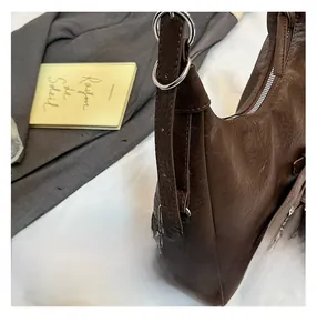 Detail of dark brown leather tote bag showing silver metal ring buckle and texture