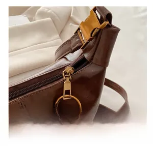 Close-up of dark brown leather bag showing golden metal hardware and smooth zipper detail