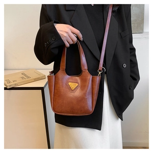 Brown retro tote bag with triangular metal logo shown with stylish model outfit