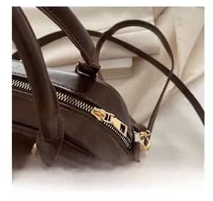 Detailed close-up of a premium dark brown PU leather bag with smooth golden metal zipper