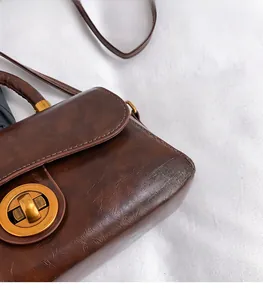 Close-up of brown vintage leather bag showing gold ring lock and glossy oil wax texture