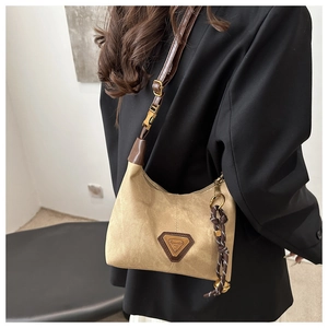 Detail of camel canvas shoulder bag with dark brown trim and metallic logo on black suit