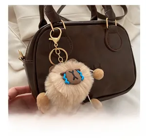 Close-up of fluffy faux fur round bag charm with cartoon face on brown leather bag