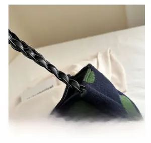Close-up of woven leather strap and dark blue plush fabric with green polka dots