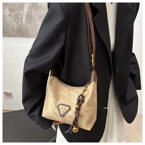 Detail of vintage beige shoulder bag with brown leather strap and decorative charms