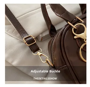 Detail of dark brown leather handbag featuring adjustable golden buckle and hardware