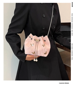 Détail d'un sac seau plissé rose avec papillons dorés, perles et bandoulière en chaîne