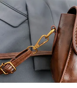 Close-up of brown vintage leather handbag featuring glossy oil finish and gold metal buckle