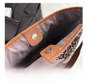 Detail of the leopard print tote bag showing metal magnetic closure and brown leather trim